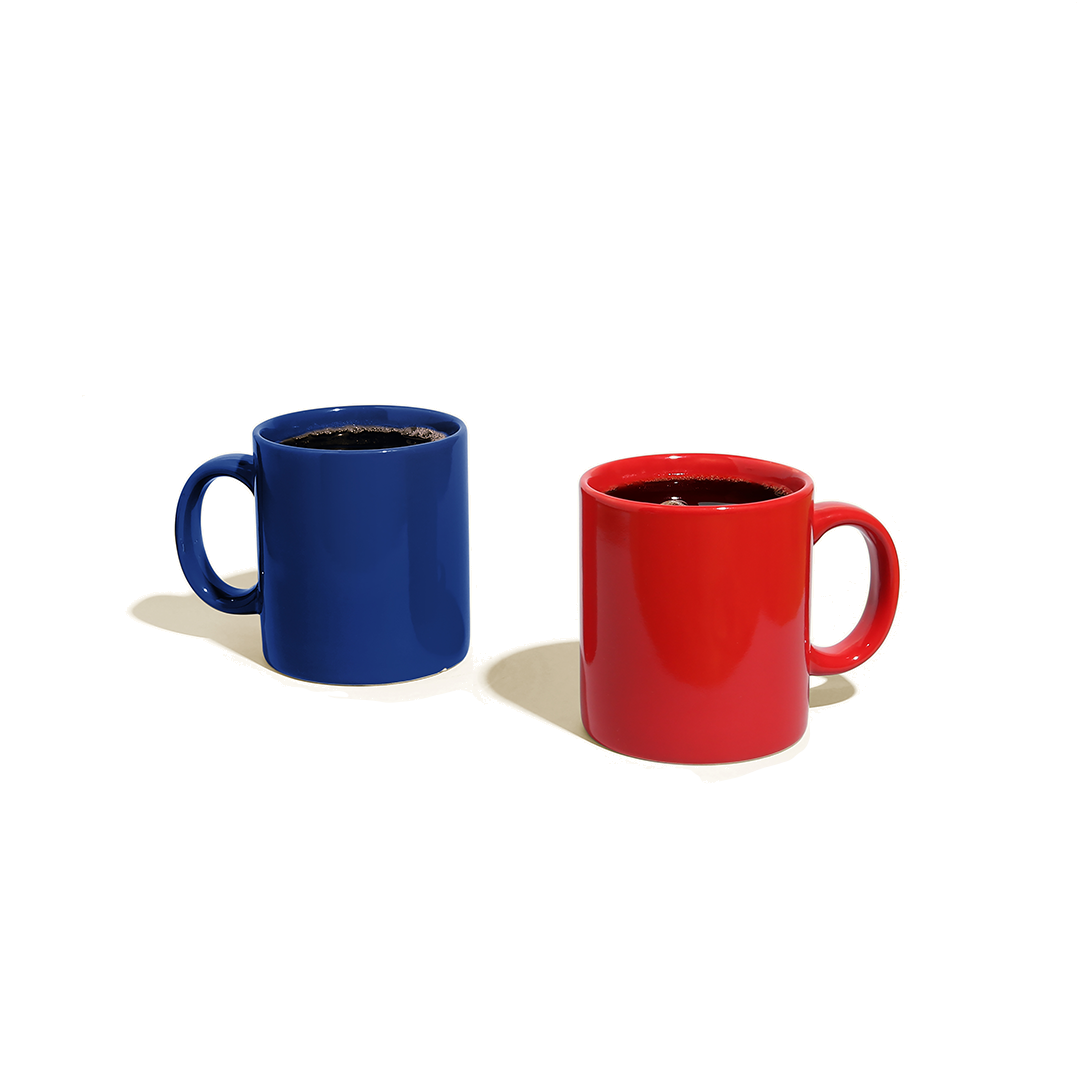Two adjacent full coffee mugs, one red and one blue.